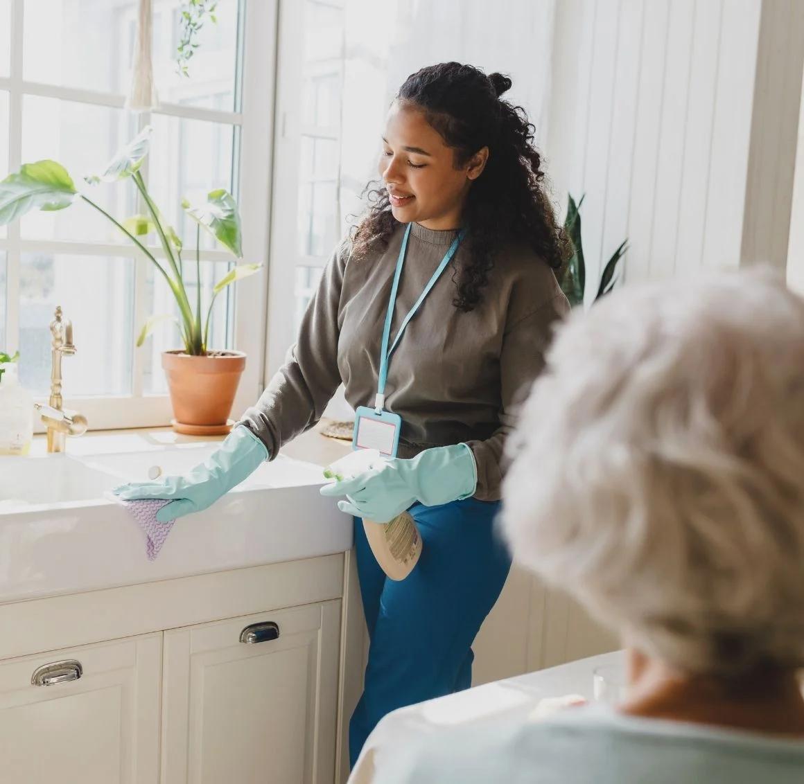 caregiver-cleaning-kitchen-sink-for-senior-woman caregiver helping with light housekeeping