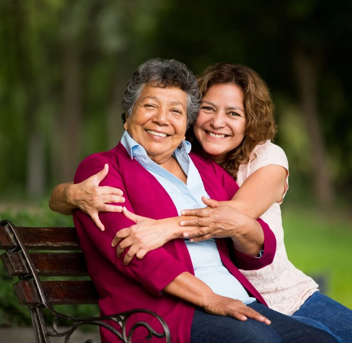 daughter-hugging-senior-mother-on-park-bench caregiver providing personal care services
