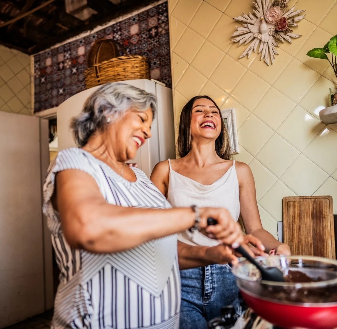senior-woman-and-daughter-stirring-pot-in-kitchen caregiver assisting senior with meal preparation